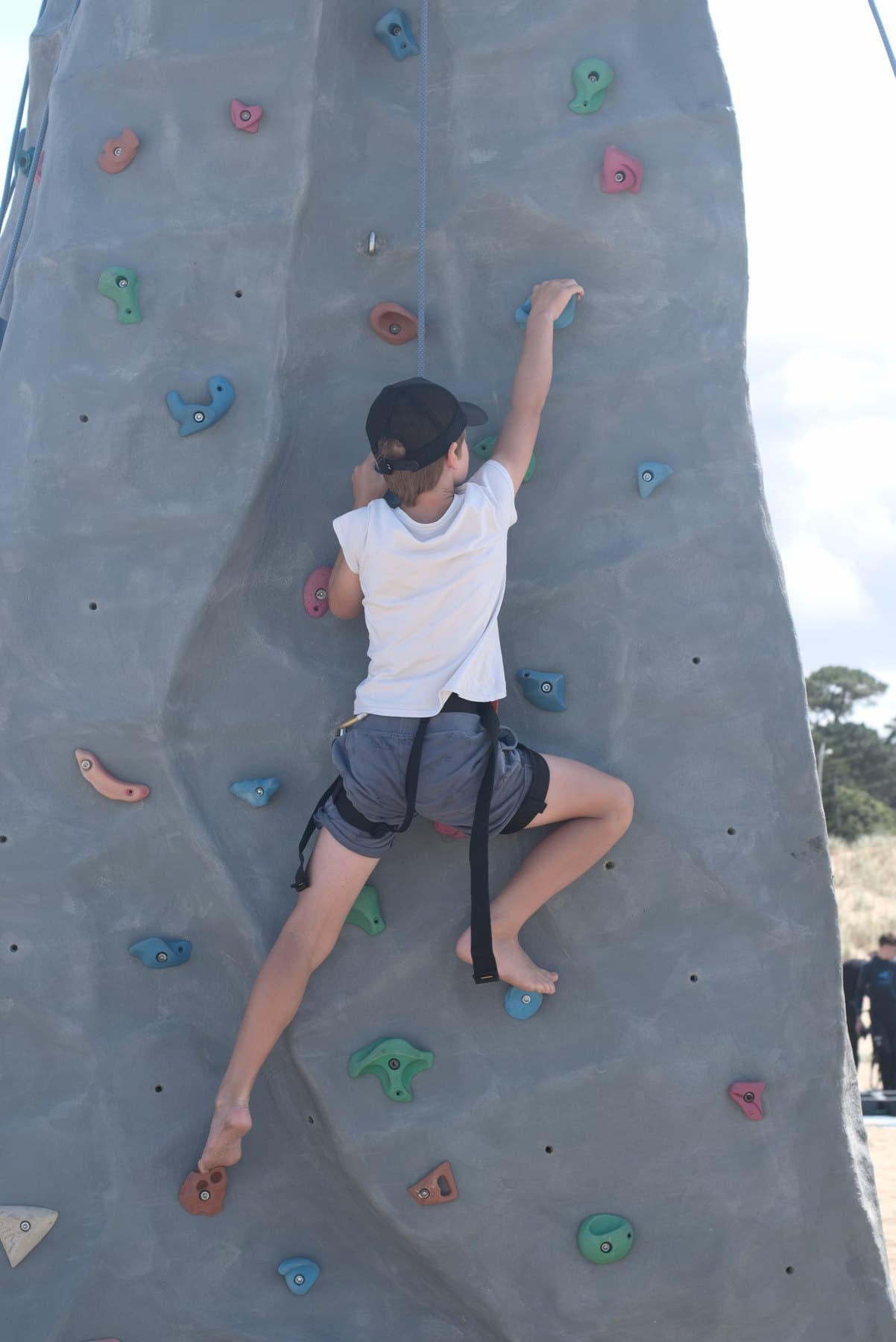 Un jeune grimpeur en pleine progression sur la face du mur